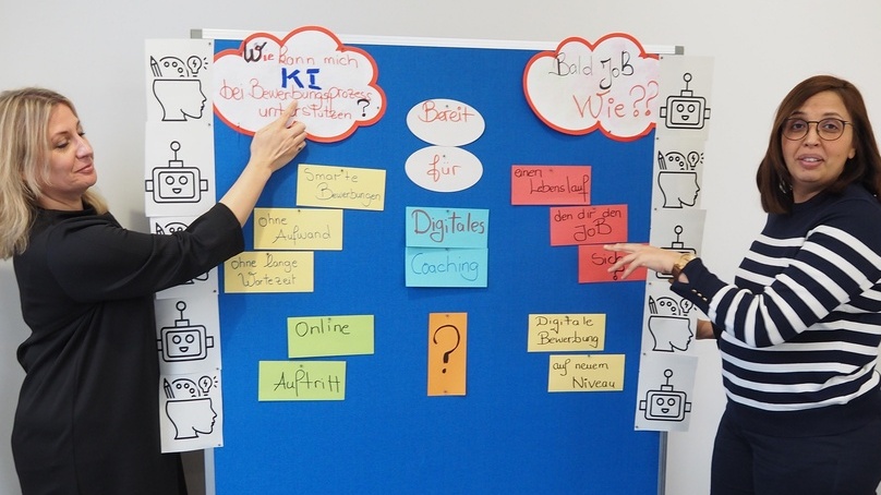 Borbála Harcsa-Zics (links) und Mouna Habassi stellen das Konzept von BALD JOB an einer Pinnwand vor.